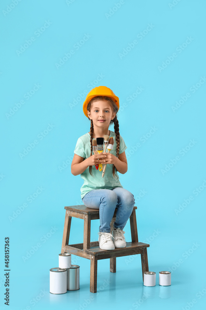 Little girl with paint brushes on blue background