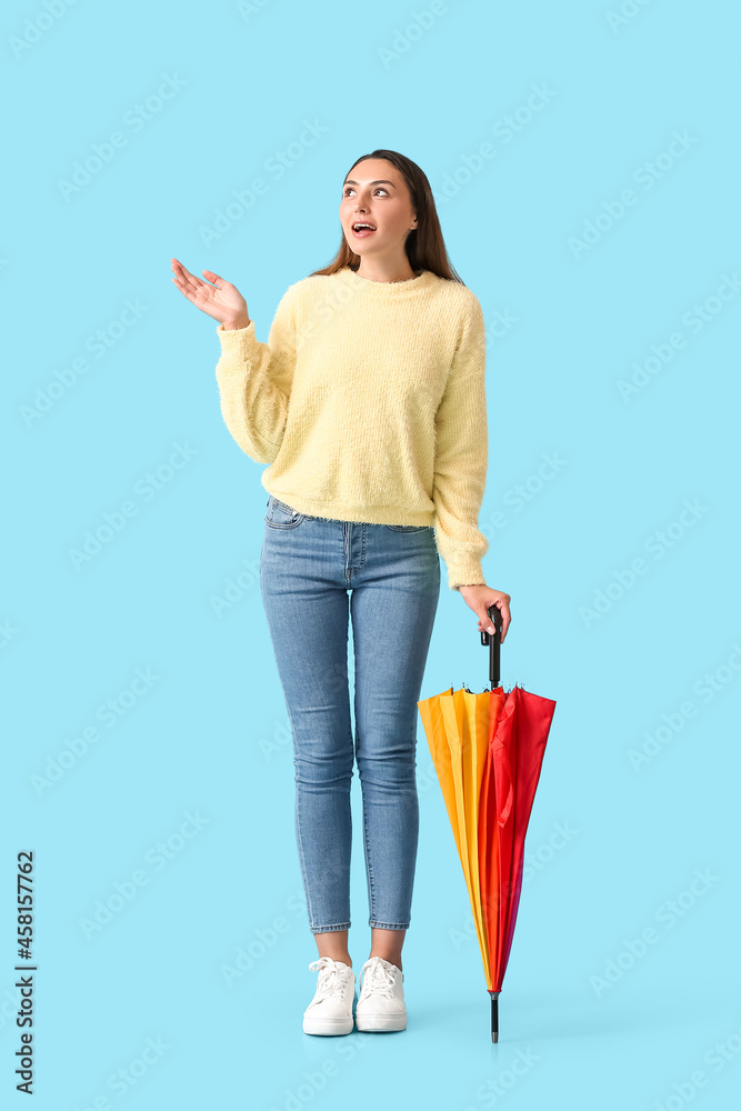 Beautiful young woman with umbrella on color background