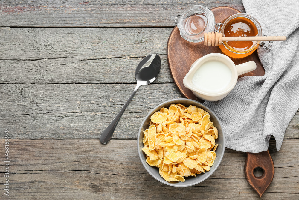 Composition with tasty cornflakes, milk and honey on wooden background