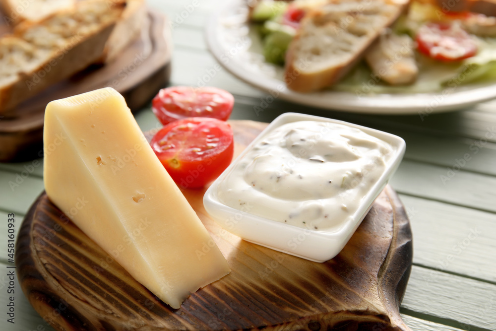 Bowl of tasty Caesar salad and parmesan cheese on table