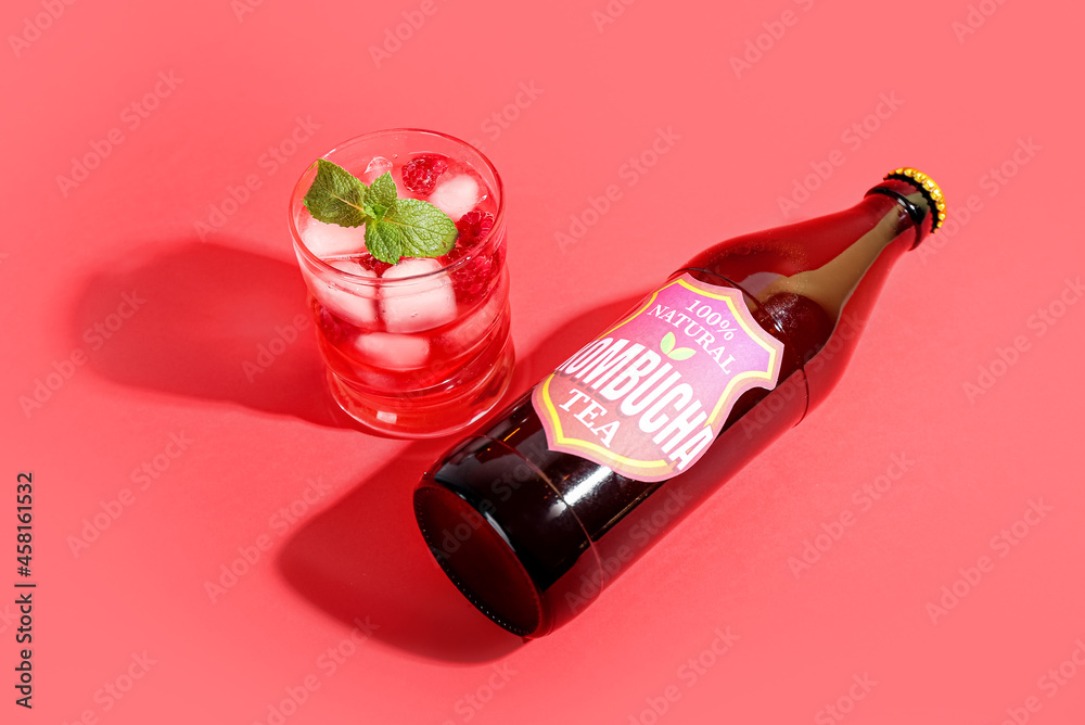 Glass and bottle of tasty kombucha tea with raspberry on color background