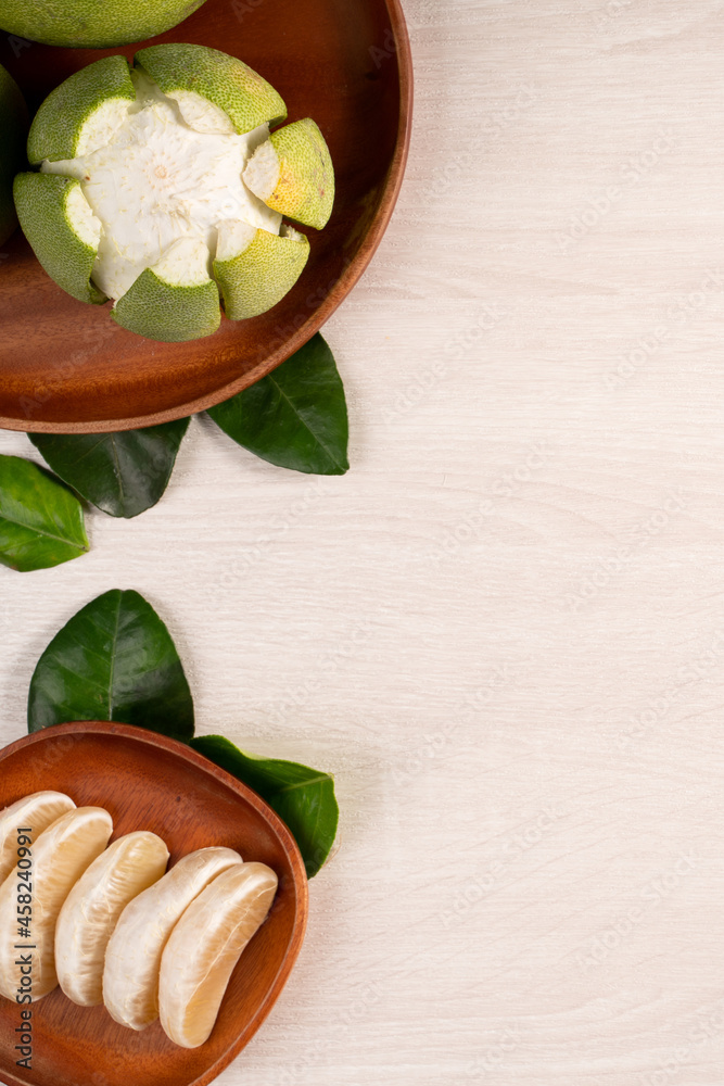 Fresh pomelo fruit on bright wooden table background.