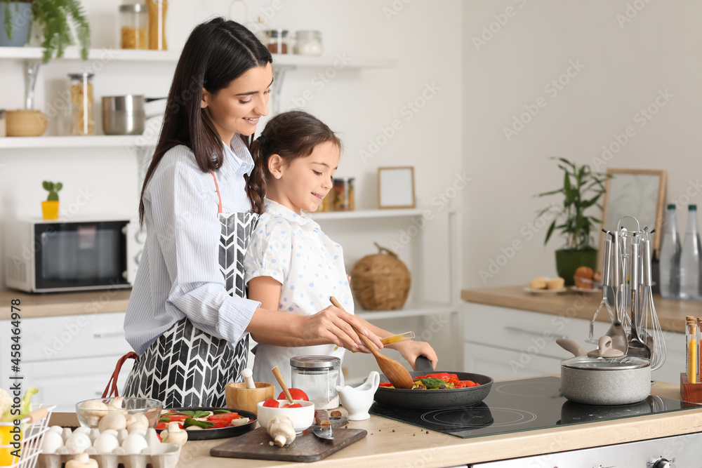 年轻的母亲和女儿在家的厨房里一起做饭