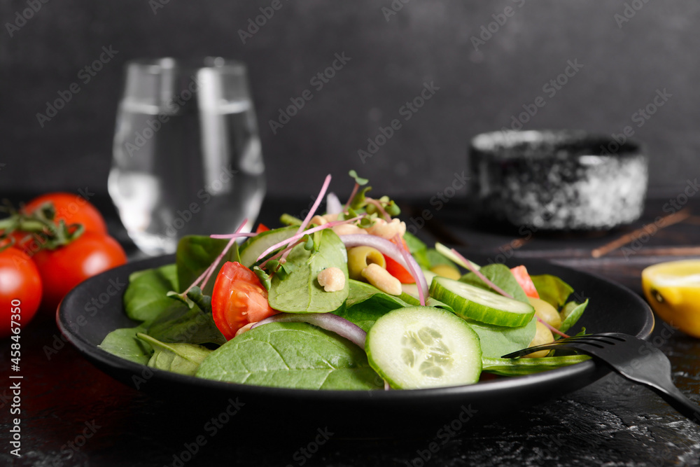 Plate with healthy salad and peanuts on dark background