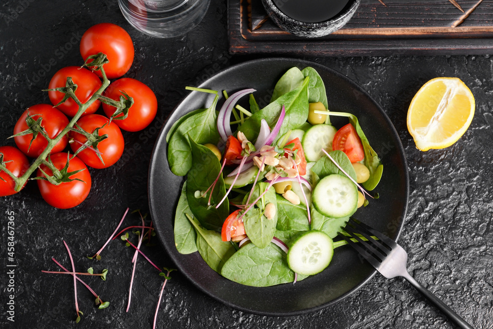 Plate with healthy salad and peanuts on dark background