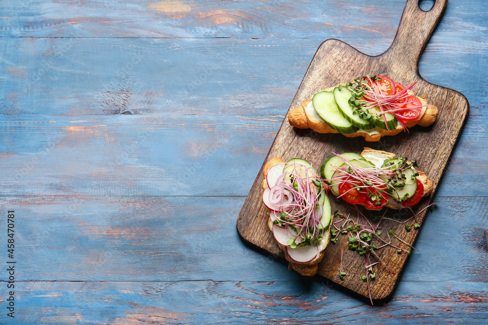 Tasty croissants with vegetables and micro green on color wooden background