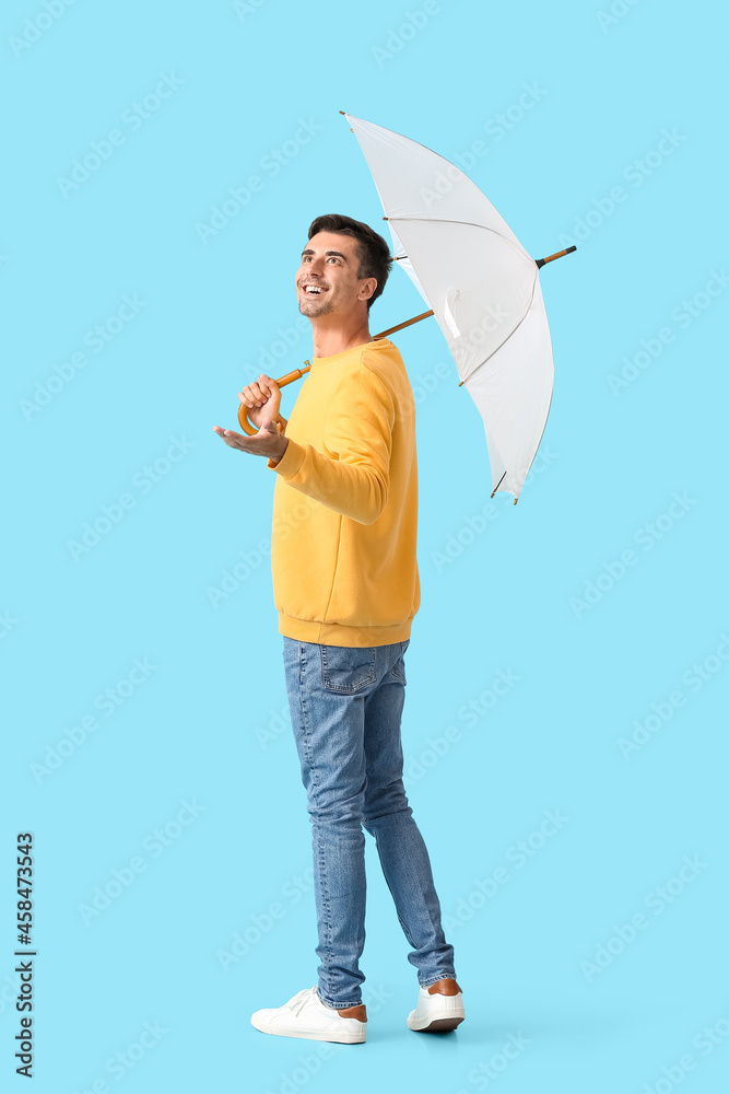 Stylish young man with umbrella on color background