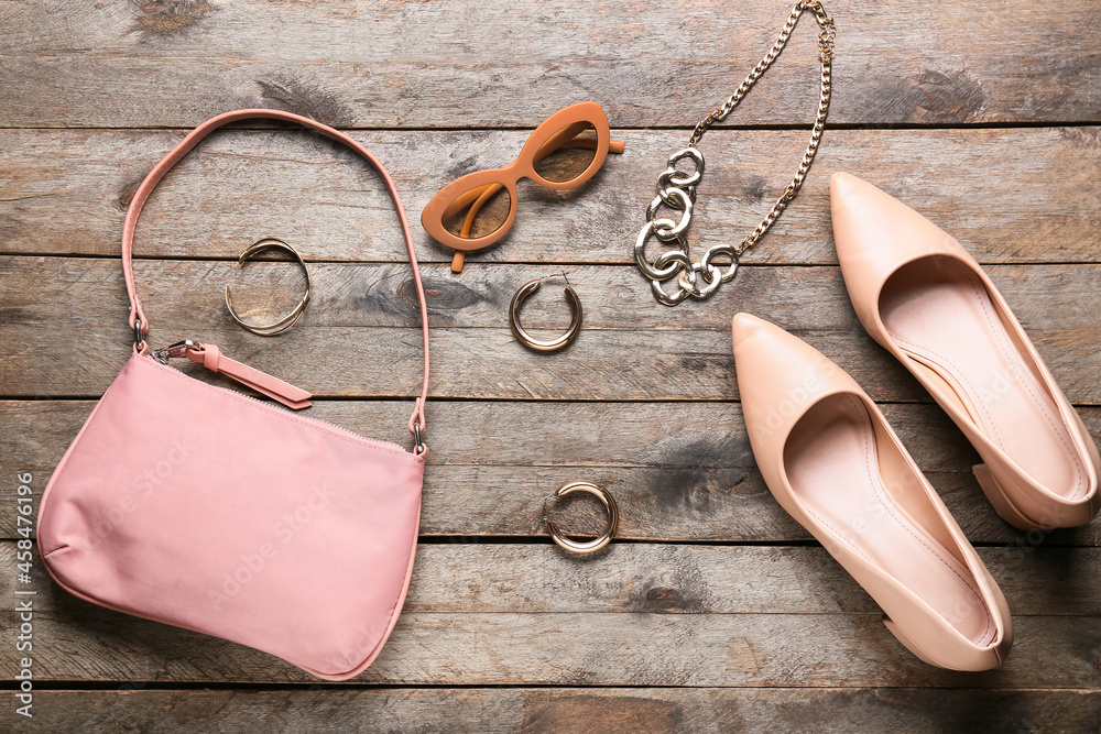 Stylish female handbag and accessories on wooden background