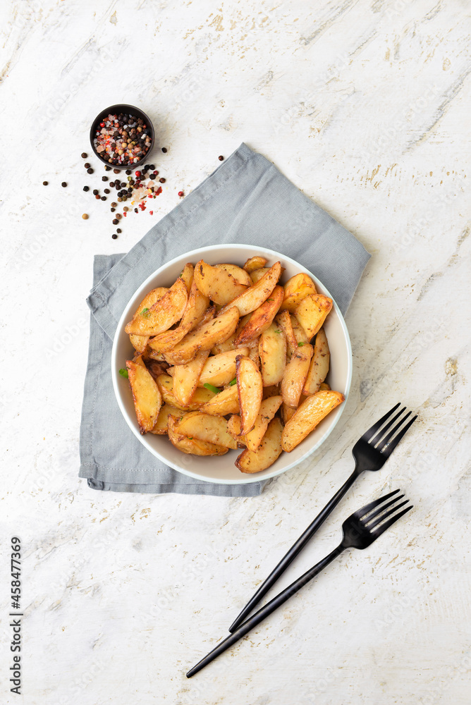 Bowl with tasty baked potato on light background