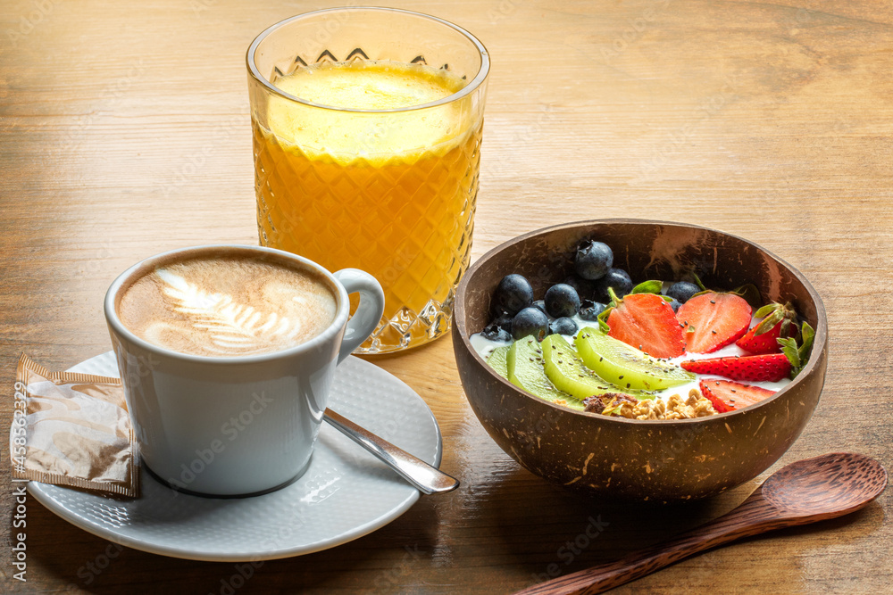 Close up of healthy breakfast with fresh fruit bowl, orange juice and creamy coffee.