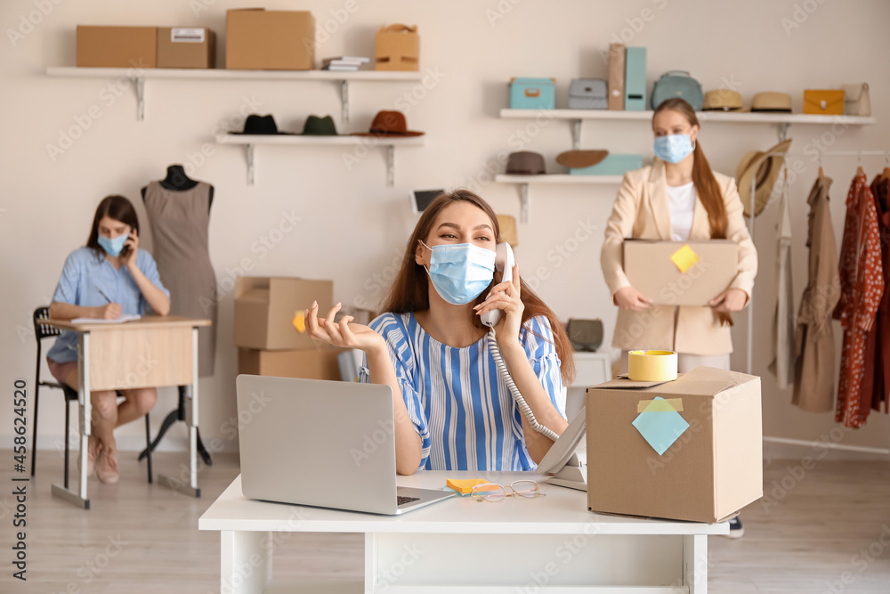 Female business owner in medical mask processing order in shop