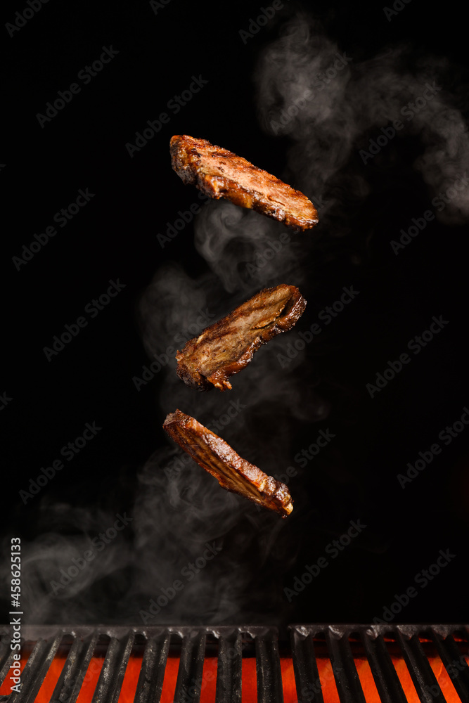 Flying beef brisket in smoke over grill on dark background