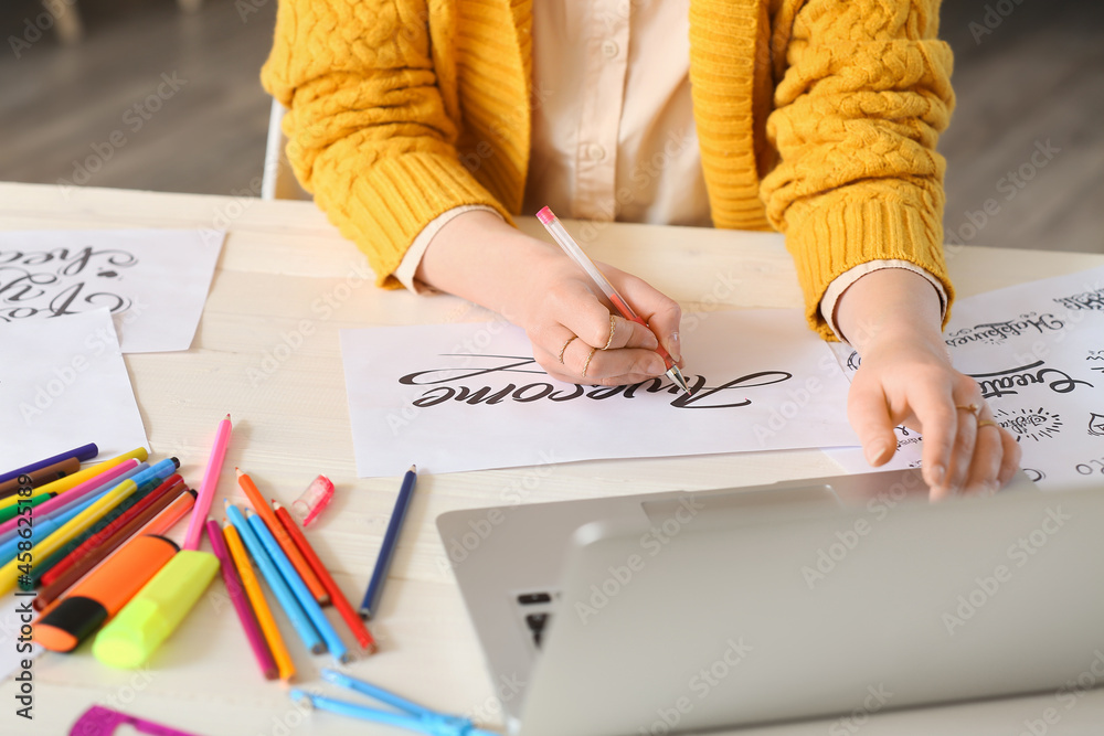 Young female calligraphist working in office