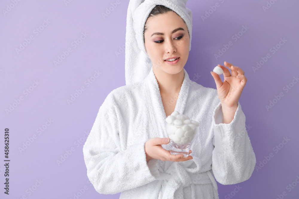 Beautiful young Asian woman with cotton wool on color background