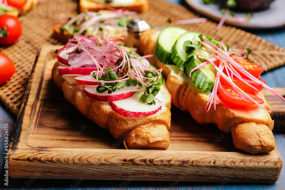 Tasty croissants with vegetables and micro green on table, closeup