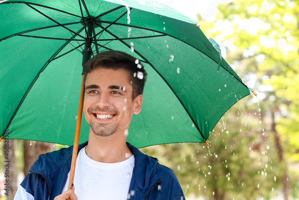 雨天公园里带伞的英俊年轻人