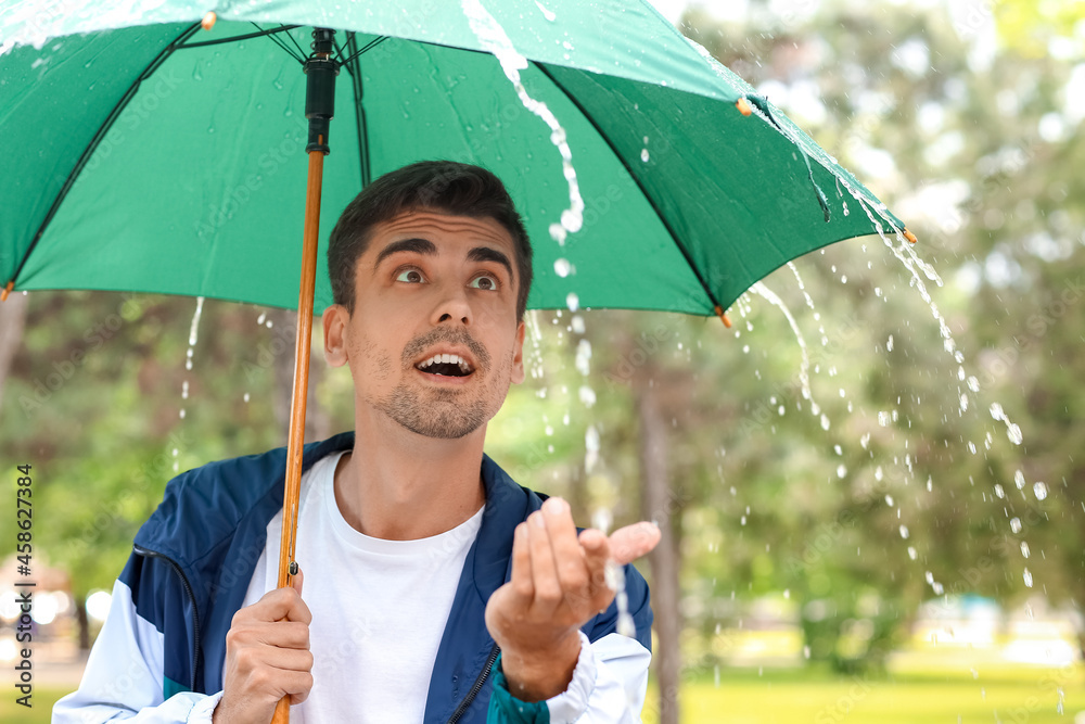 雨天公园里带伞的英俊年轻人