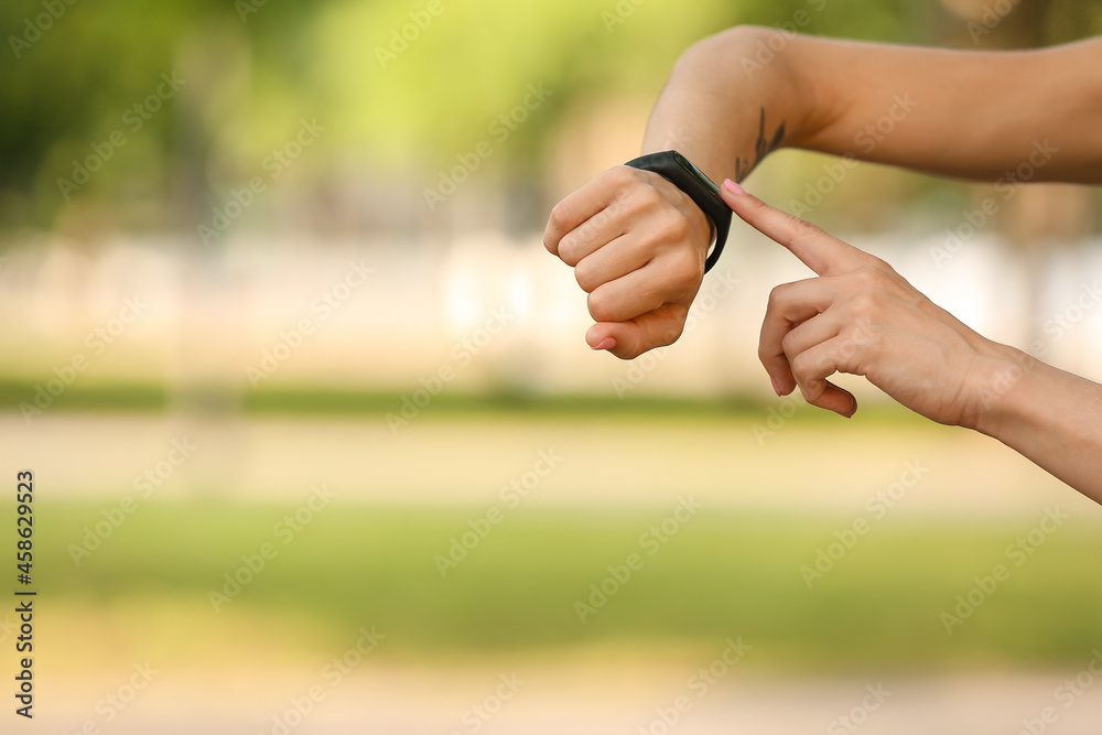 Sporty female runner checking pulse outdoors