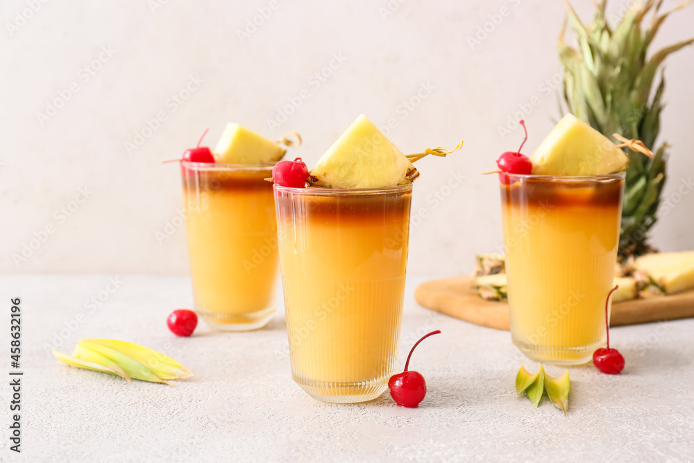 Glasses with delicious mai tai cocktail garnished with cherry and pineapple slices on light table