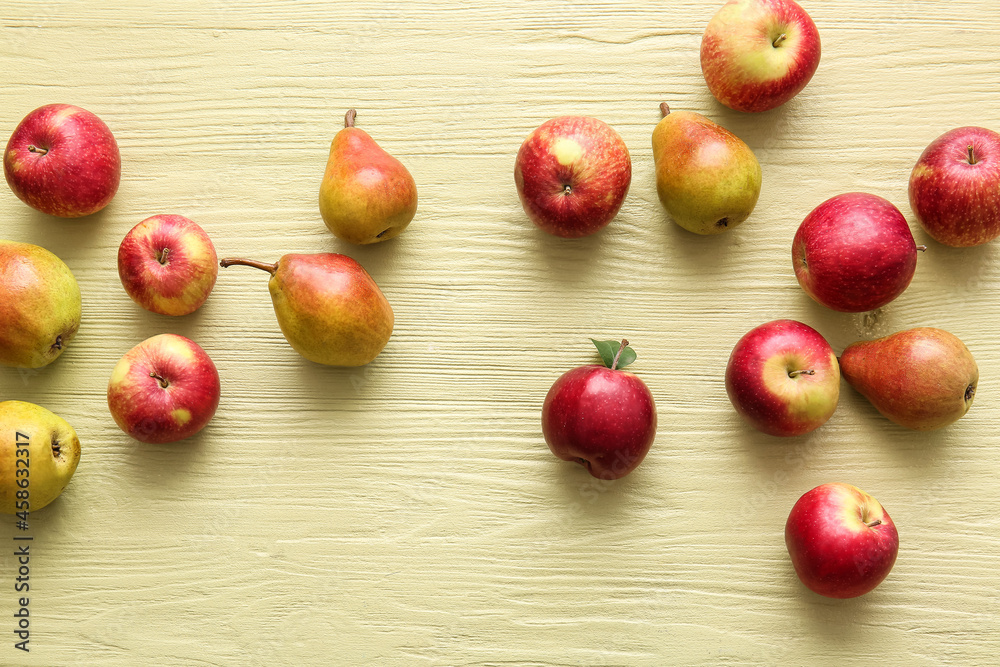 Ripe pears and apples on color wooden background