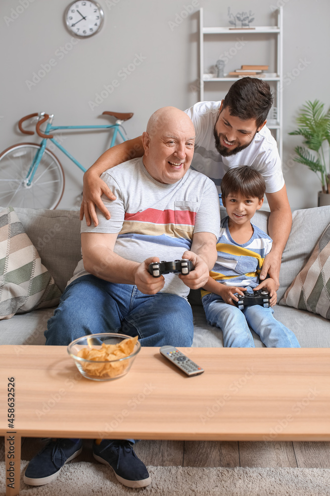 Man, his little son and father playing video game at home