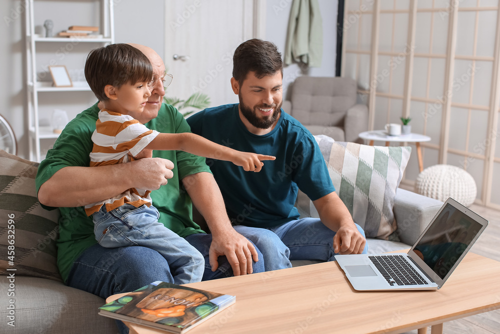 Happy man, his little son and father video chatting at home