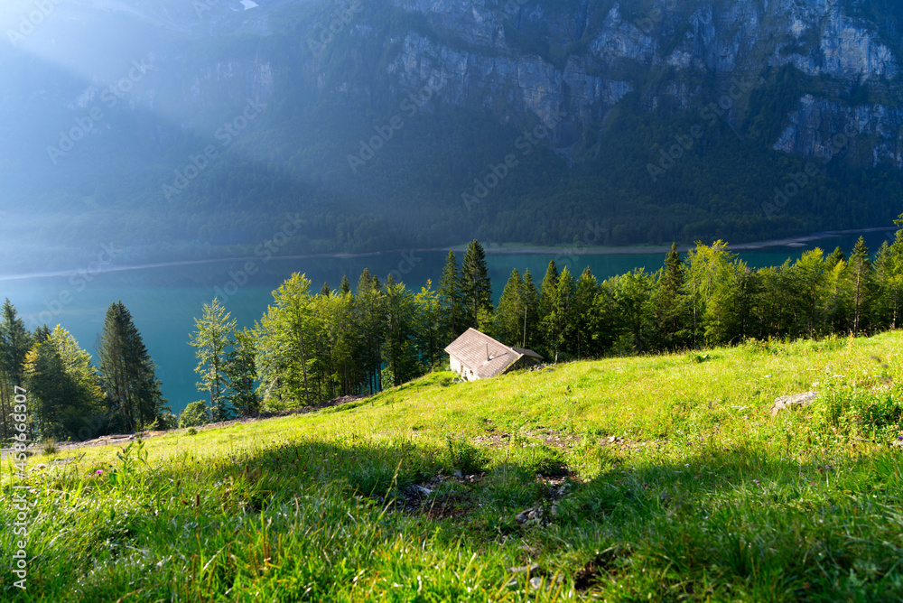 Lake Klöntal with cabin at a beautiful late summer morning with reflections in calm water. Photo tak