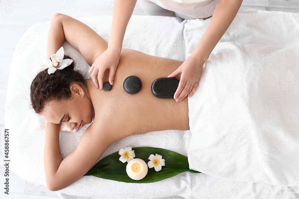 Beautiful young African-American woman relaxing in spa salon, top view