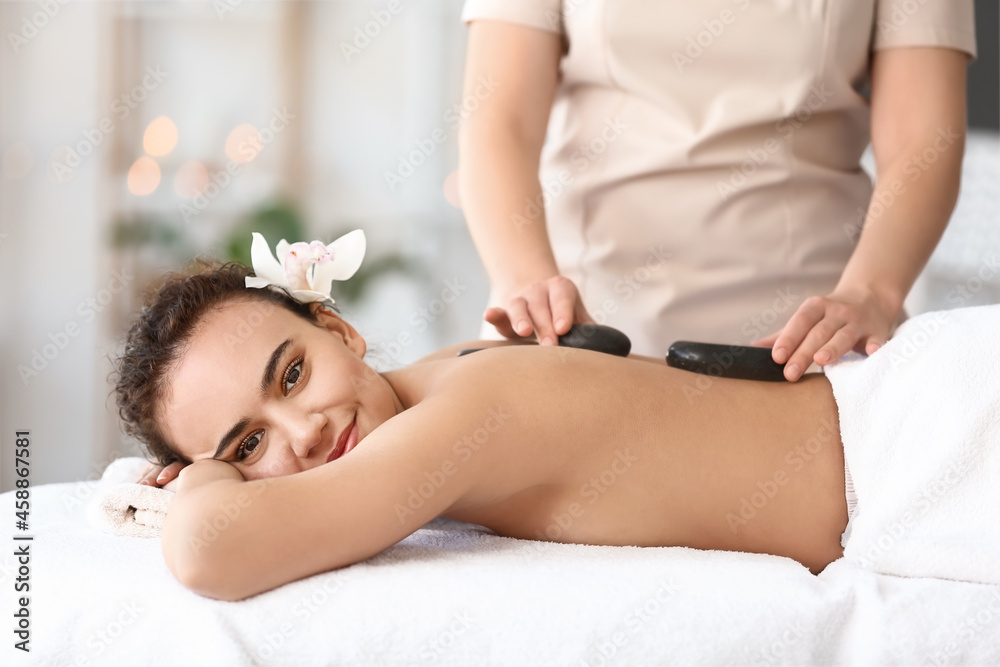 Beautiful young African-American woman relaxing in spa salon