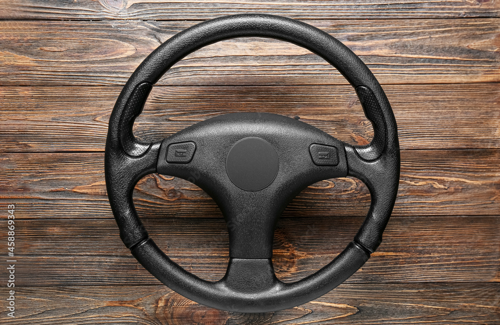 Stylish steering wheel on wooden background