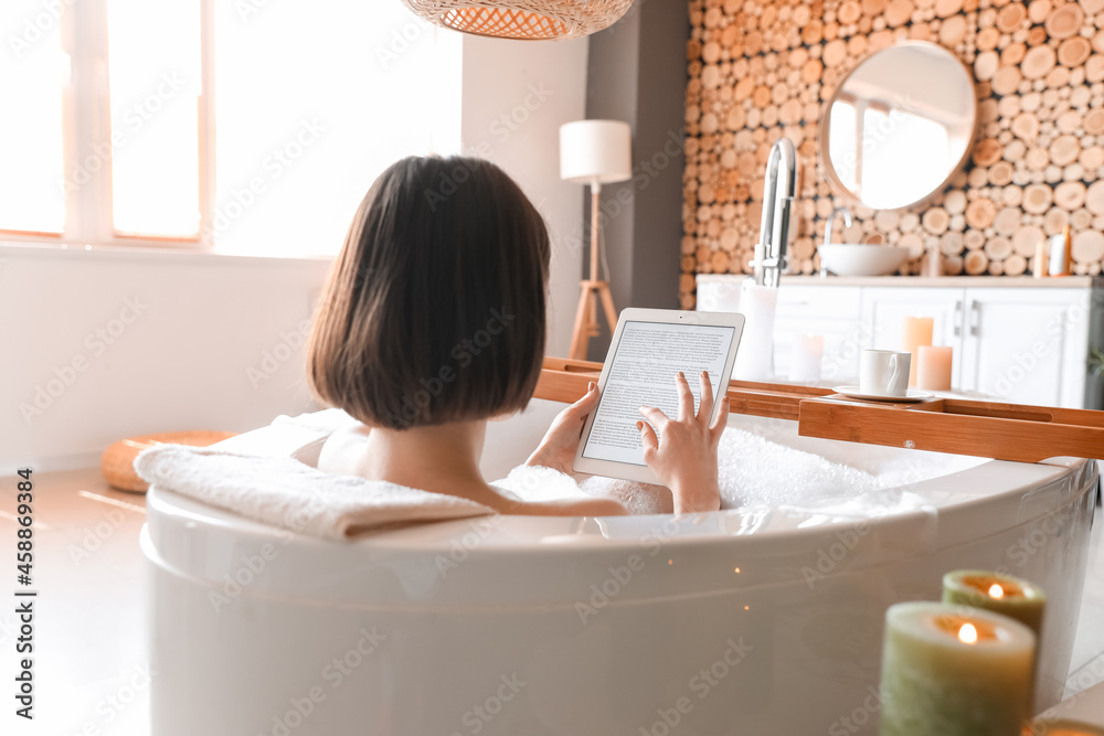 Young woman using tablet computer while taking bath at home