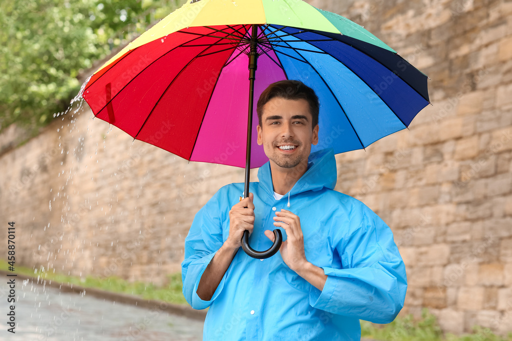 Handsome young man with umbrella outdoors