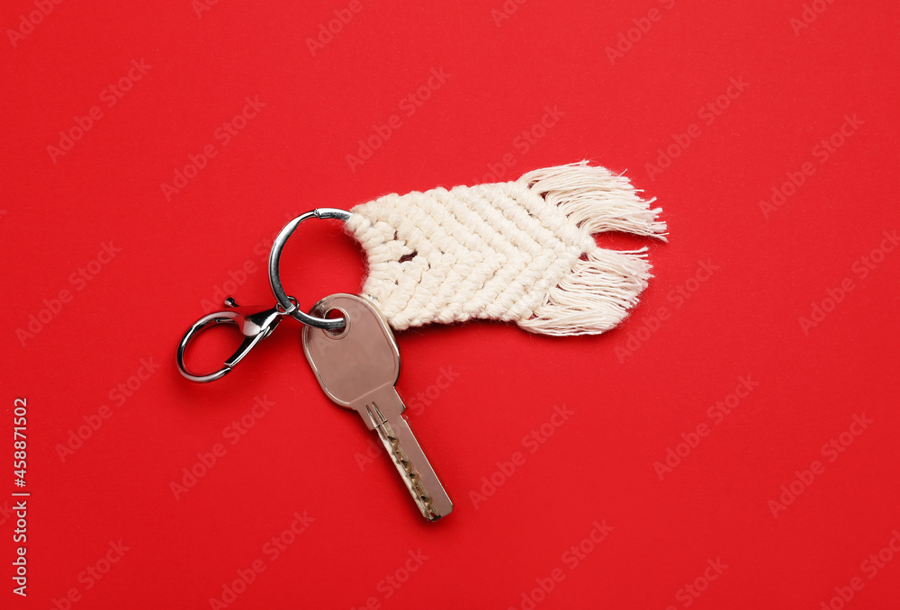 Key with handmade cotton keychain on color background