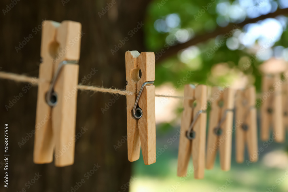 Clothespins hanging on laundry line outdoors, closeup