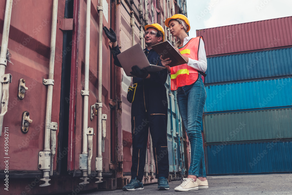 Industrial worker works with co-worker at overseas shipping container yard . Logistics supply chain 