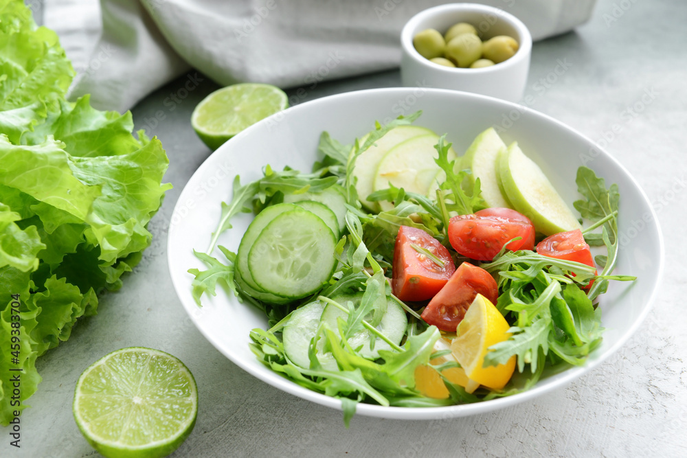 Plate with fresh salad on light background