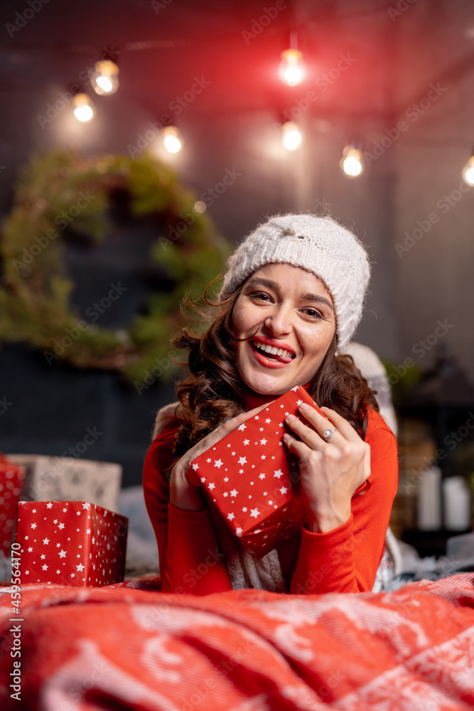 Beautiful young woman looking at the camera and holding her new year presents. Lady dressed in winte