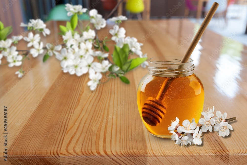 Sweet honey jar surrounded spring flowers blossoms.