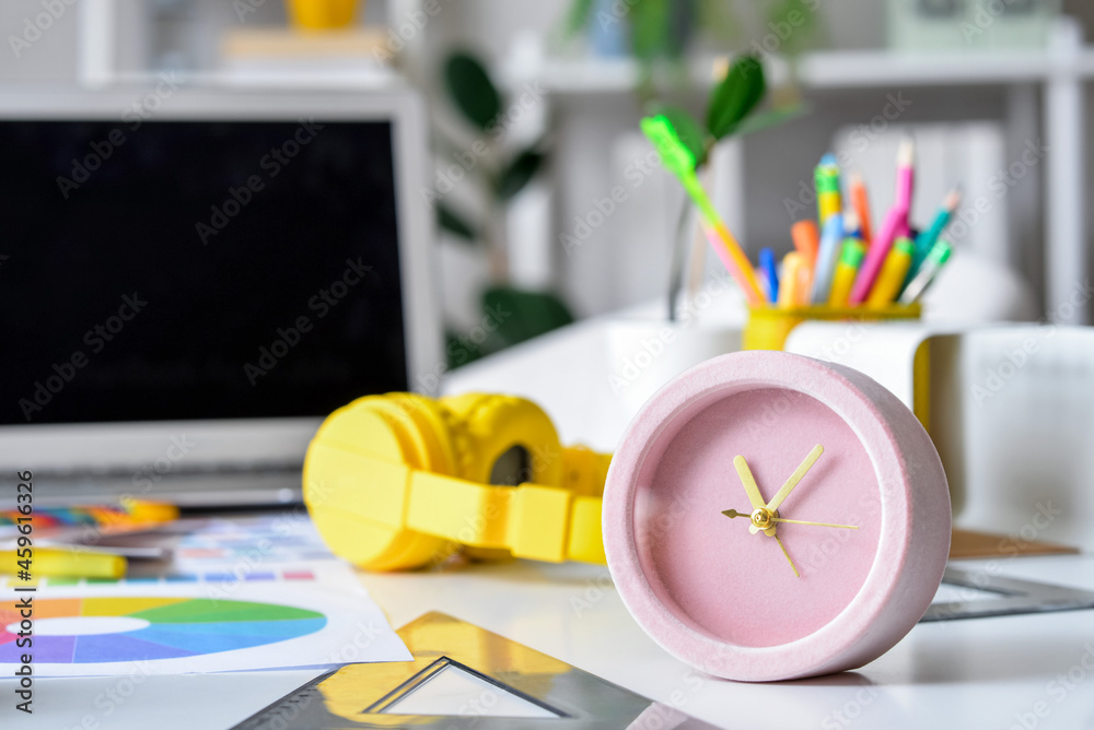 Comfortable workplace with alarm clock and headphones in office, closeup