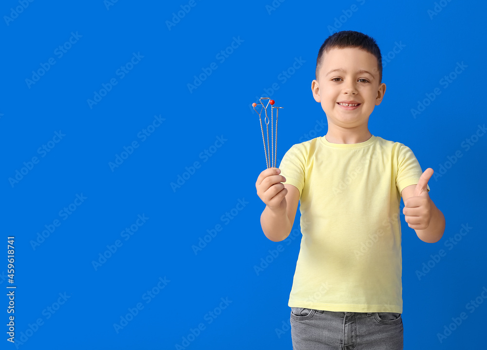 Little boy with logopedic tools showing thumb-up on color background