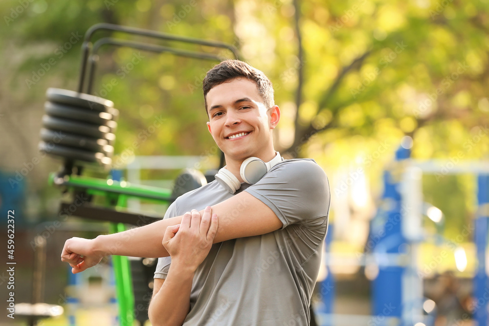 Handsome young man with headphones exercising on sport ground