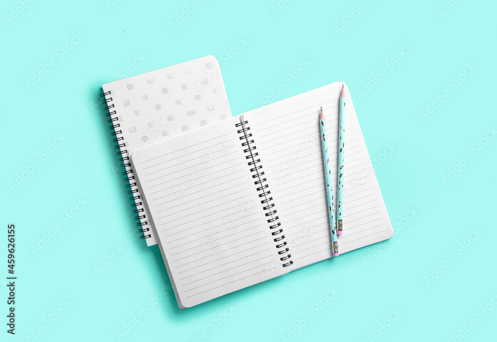 Stylish notebooks and pencils on color background