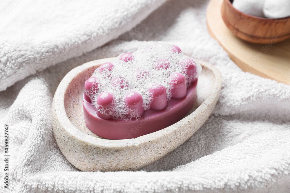 Bowl with massage soap bar on fabric background, closeup