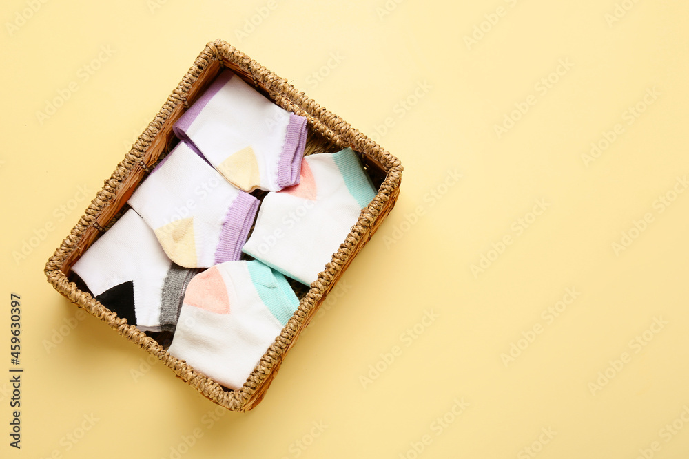 Wicker basket with stylish socks on color background