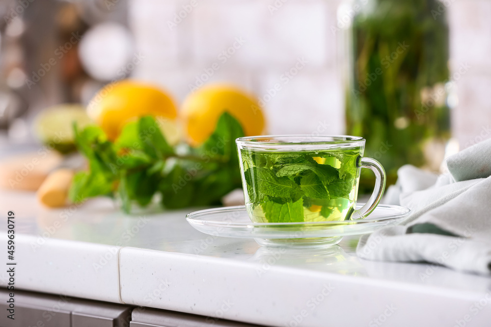 Glass cup of tasty mint tea on table in kitchen