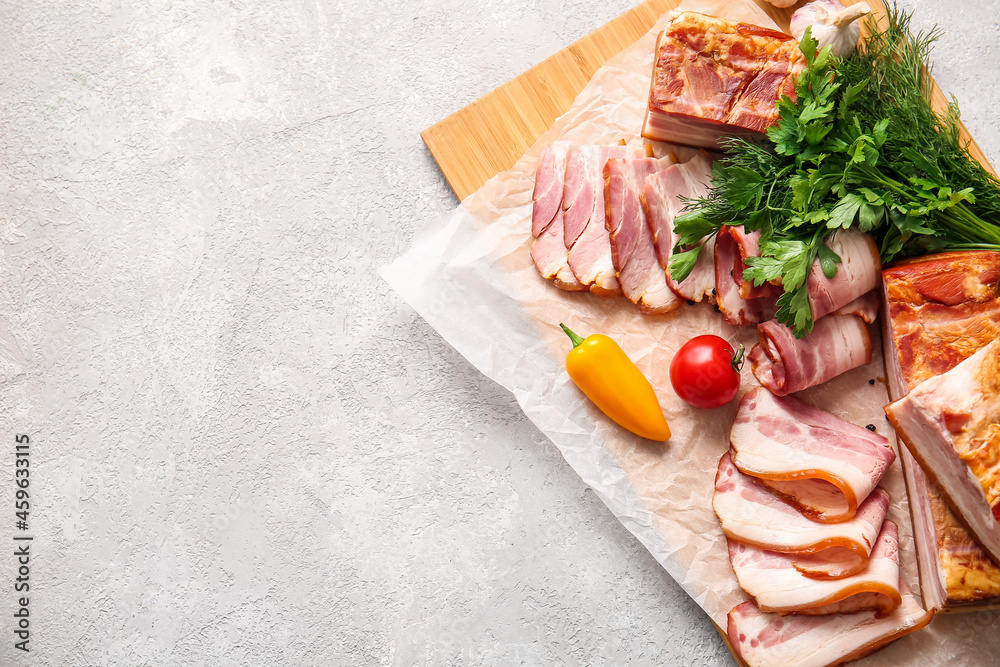 Wooden board with tasty smoked bacon and fresh vegetables on light background