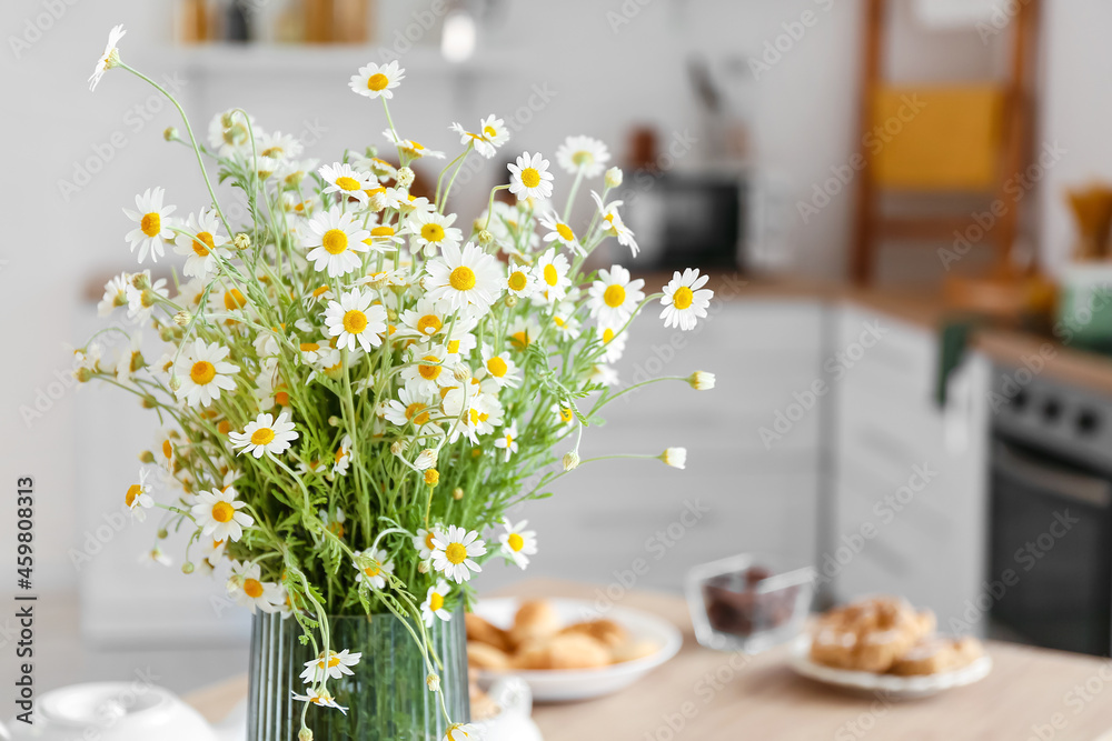 Vase with chamomiles on table in kitchen