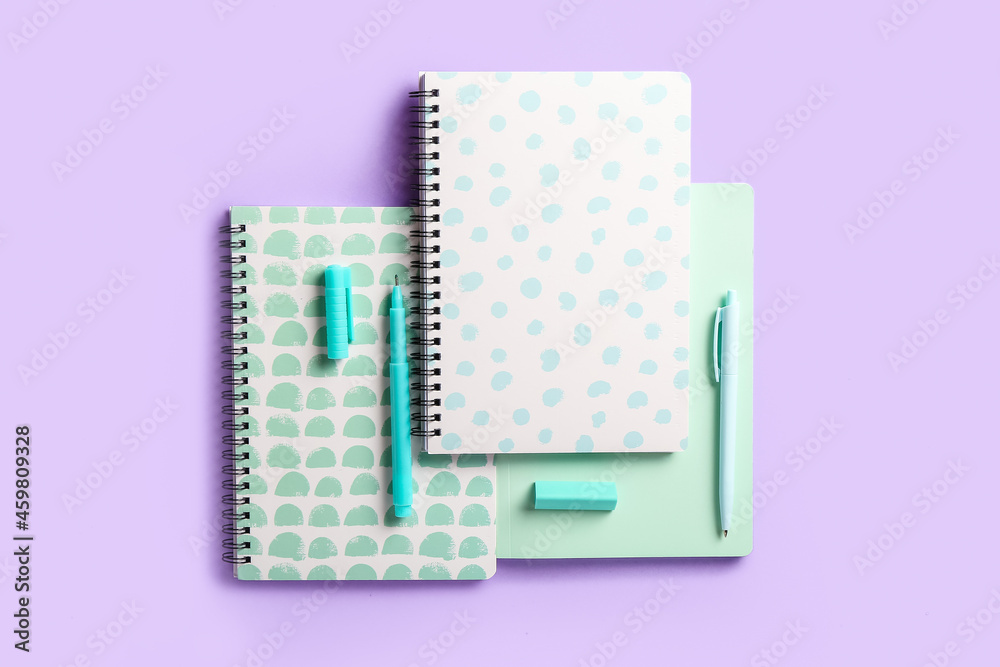 Stylish notebooks, pens and eraser on color background