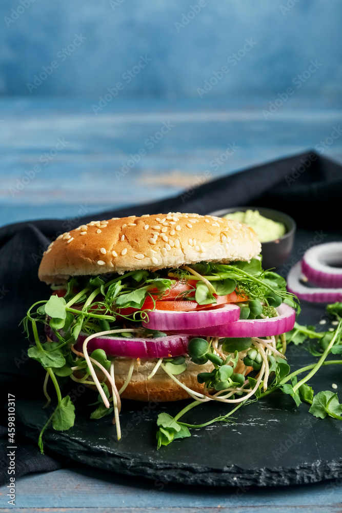 Board with tasty vegetarian burger on blue wooden background