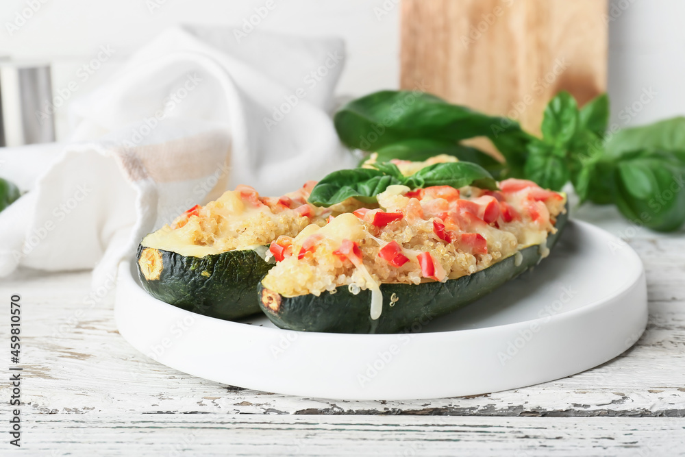 Plate with quinoa stuffed zucchini boats on light wooden background